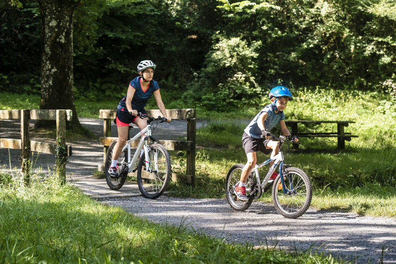 kobieta i dziecko jadące na rowerach po parku