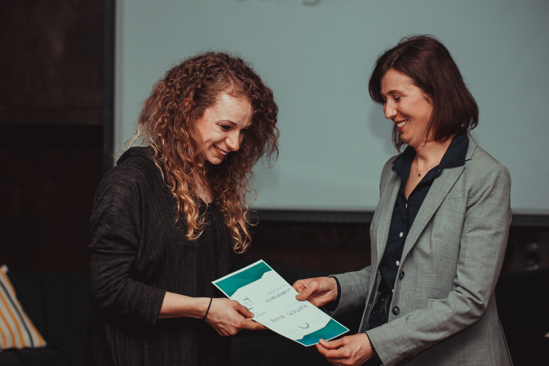 kobieta wręczająca dyplom drugiej kobiecie