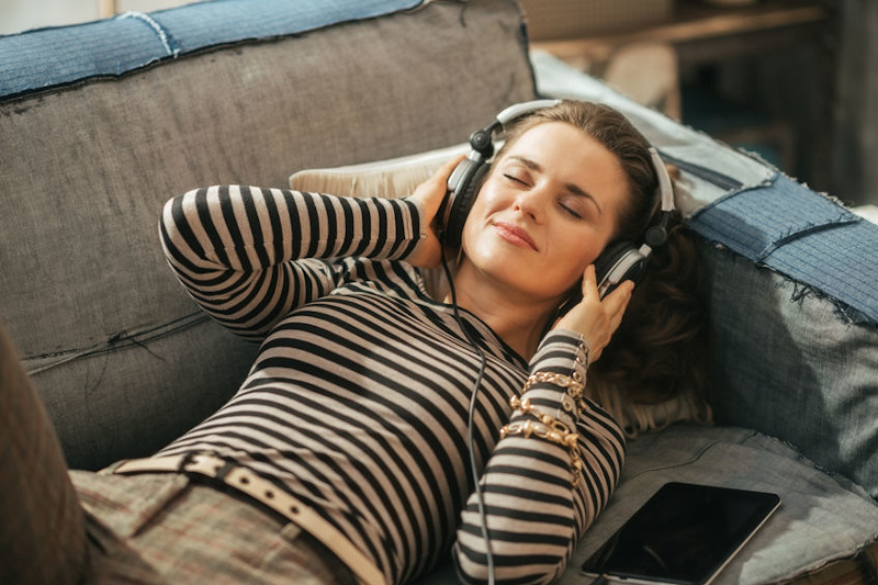 kobieta z słuchawkami na uszach relaksująca się na sofie