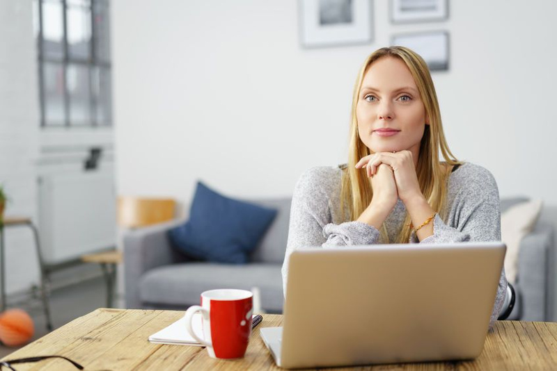 Kobieta przy laptopie w domowym biurze patrzy w obiektyw