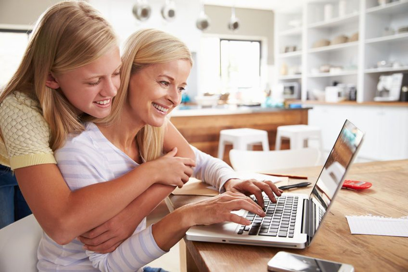 Mama pracuje w kuchni, córka przytula się do mamy