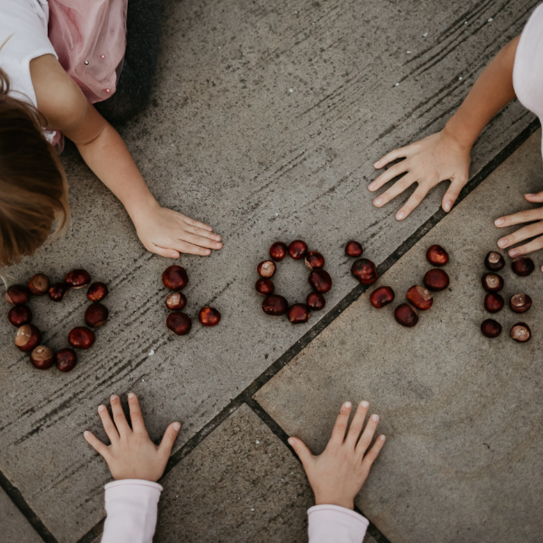 ręce dzieci napis Love z kasztanów